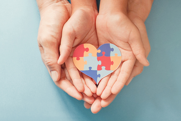 Adult holding child hand with autism puzzle pieces