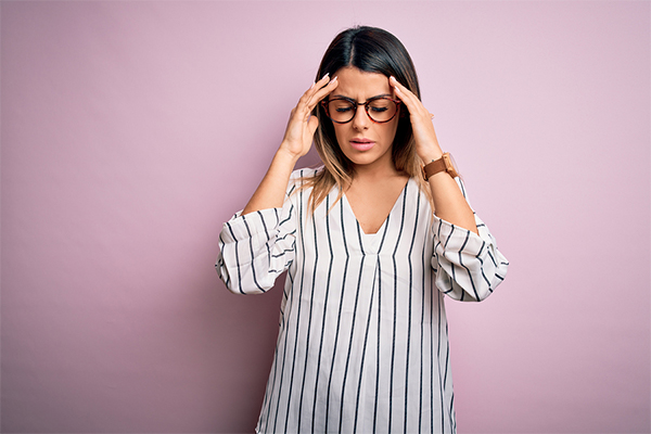 Young woman holding her face because she has a migraine