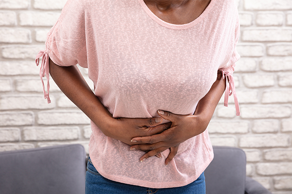 Young black woman holding stomach in pain from being on her period.