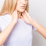 Woman holding thyroid glands on her neck