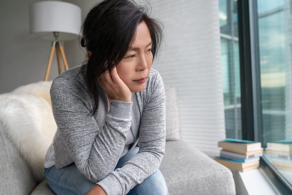 Older Asian woman sitting at home sad