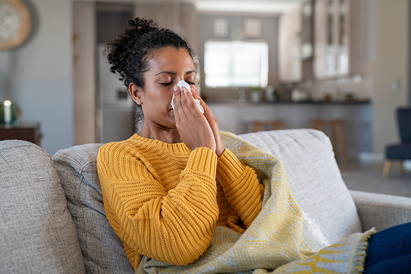 Woman blowing her nose at home