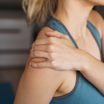 Young woman holding her shoulder in pain