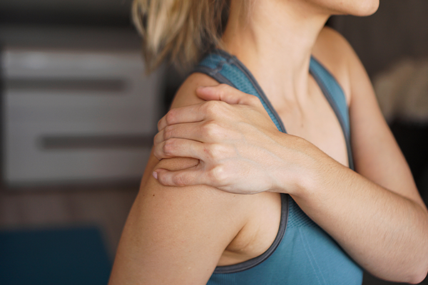 Young woman holding her shoulder in pain