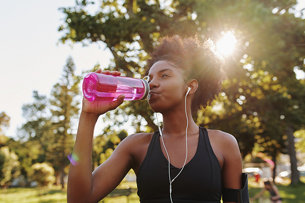 Black woman drinking water after run