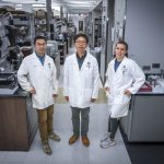 In this photo, you see two men and a woman standing and posing for a photo inside a science lab.