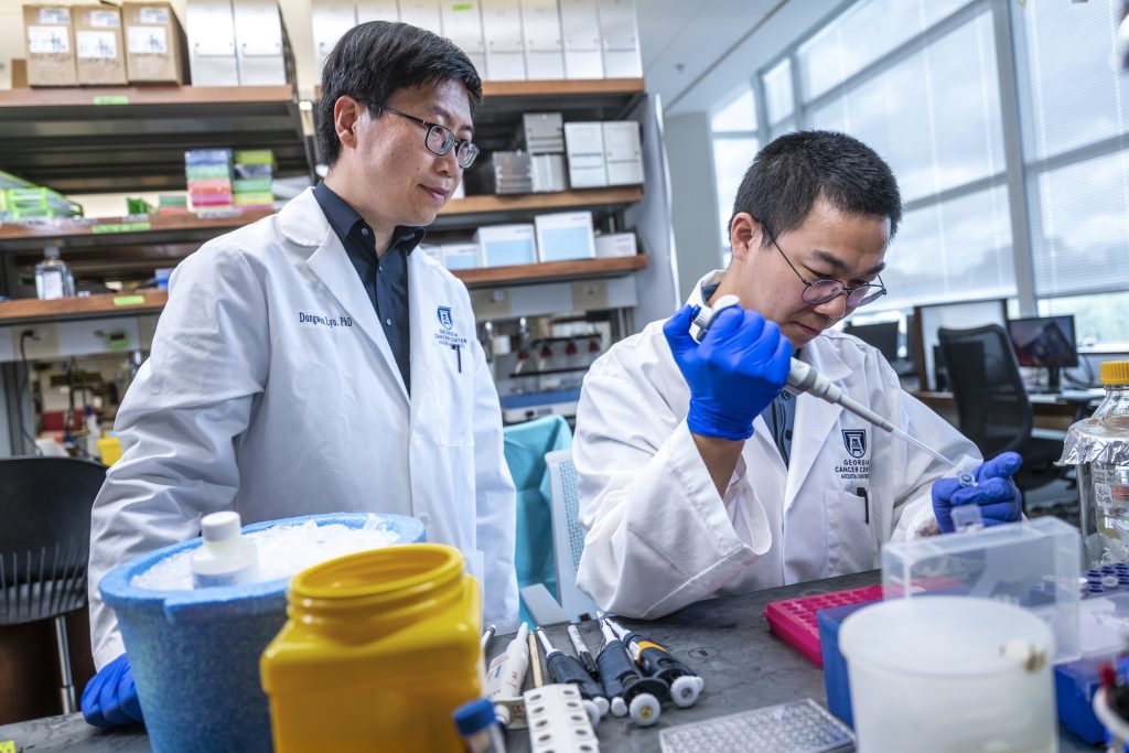 In this photo, you see two men working inside a science lab doing research on different proteins found in cancer cells.