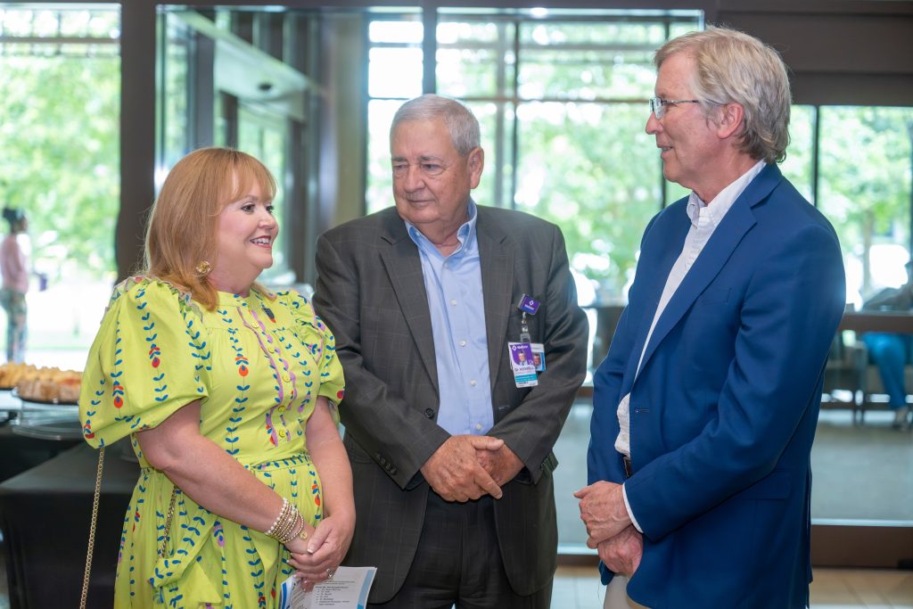 In this photo, you see three, two men and one woman, standing and talking.