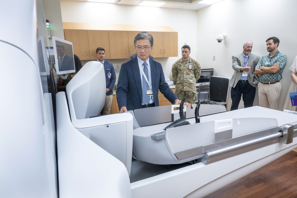 In this photo, you see a group of people standing around the Elekta Esprit Gamma Knife machine.